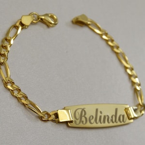 Puede incluir: Pulsera de cadena dorada con una placa rectangular grabada con el nombre "Belinda".