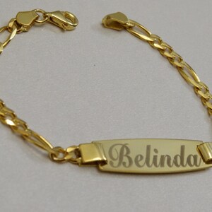 Puede incluir: Un brazalete de cadena de oro con una placa rectangular grabada con el nombre "Belinda".