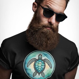 May include: Black t-shirt featuring a watercolor-style sea turtle design within a blue and green circle. The turtle has a teal shell and beige flippers. The shirt is worn by a person wearing sunglasses.