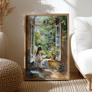 May include: A framed art print depicts a person reading by an open window. The artwork features a person in a white dress, seated on a windowsill, with a book. The window reveals a lush garden with flowers and greenery. The frame is a light brown color.