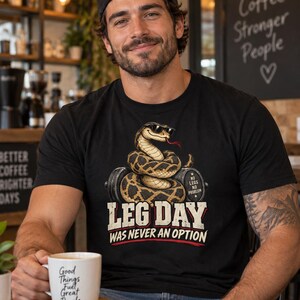 Może przedstawiać: Czarny t-shirt z krótkim rękawem z grafiką przedstawiającą węża w okularach przeciwsłonecznych owiniętego wokół hantli. Napis "NO LEGS NO PROBLEM", "LEG DAY" oraz "WAS NEVER AN OPTION" widnieje w białym i czerwonym kolorze na przodzie koszulki.