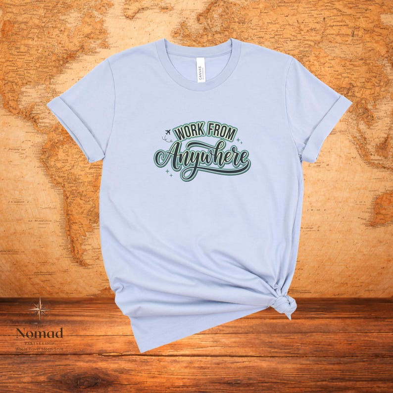 Pu&ograve; includere: T-shirt azzurra con la scritta "Work From Anywhere" in verde e bianco. La maglietta &egrave; annodata in basso e ha le maniche arrotolate. Sullo sfondo &egrave; presente una mappa del mondo.