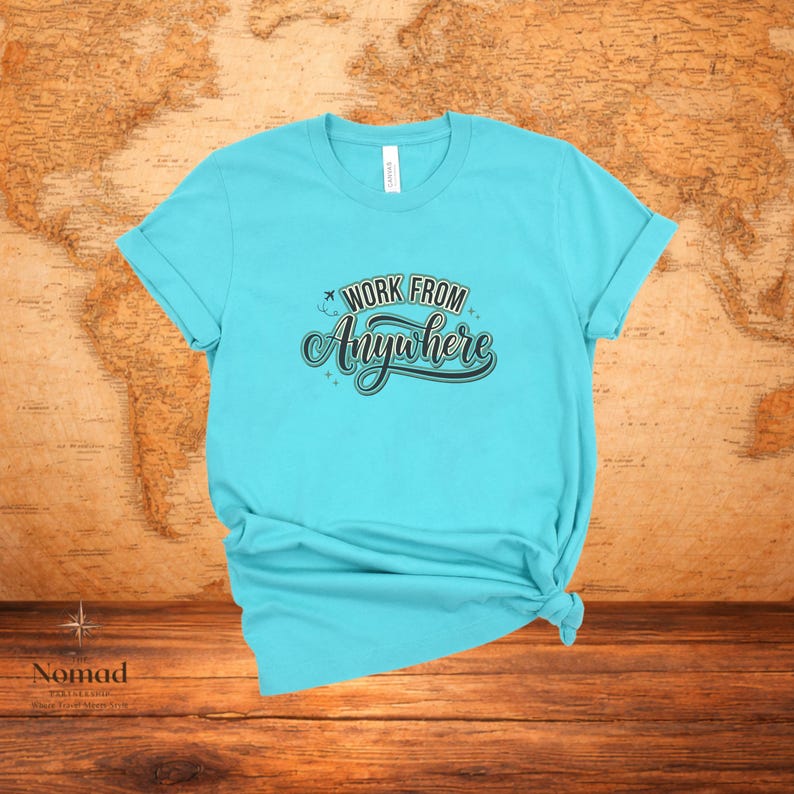 Pu&ograve; includere: Una maglietta turchese con le maniche arrotolate. La maglietta presenta la scritta "Work From Anywhere" in un carattere decorativo. La maglietta &egrave; annodata in basso. Lo sfondo &egrave; una mappa del mondo.