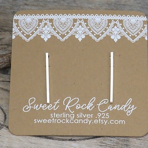 May include: A pair of sterling silver earrings on a brown card with white lace trim. The card reads "Sweet Rock Candy, sterling silver .925, sweetrockcandy.etsy.com".
