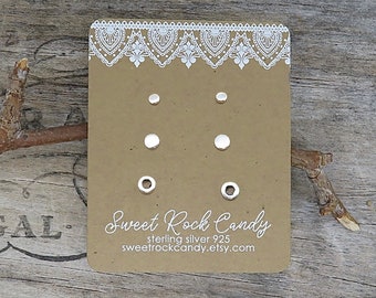 May include: A set of three pairs of silver stud earrings displayed on a rectangular brown card with white lace-style trim. The card features the text Sweet Rock Candy, sterling silver 925, and the website address sweetrockcandy.etsy.com.