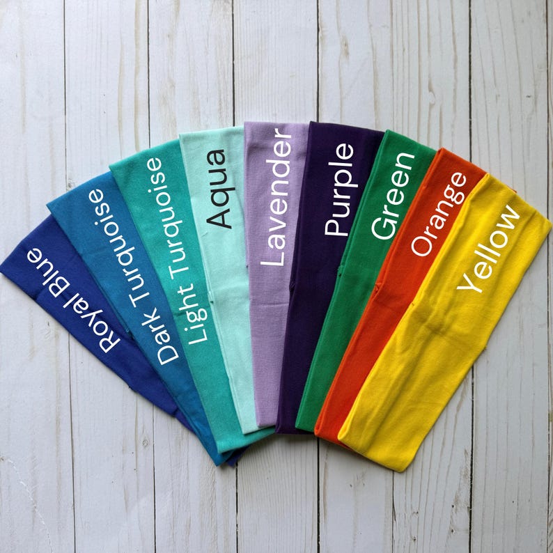 Puede incluir: Una colecci&oacute;n de ocho diademas de tela dispuestas en forma de abanico, con los colores azul real, turquesa oscuro, turquesa claro, aguamarina, lavanda, morado, verde, naranja y amarillo, cada una etiquetada con su nombre en texto blanco.