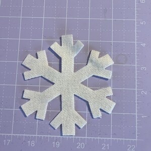 May include: A white felt snowflake ornament with a six-pointed star shape.