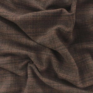 May include: Close-up of a brown fabric with a textured weave. The fabric has a mix of brown and dark gray threads, creating a subtle, mottled appearance. The material is draped, showing folds and shadows.