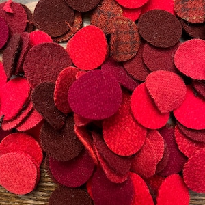 May include: A pile of red, burgundy, and brown felt circles. The circles are various sizes and are arranged in a random pattern.