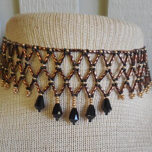 May include: A brown and black beaded choker necklace with a geometric design and black crystal drops.