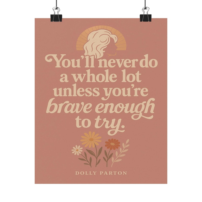 May include: A pink poster with a quote by Dolly Parton that reads "You'll never do a whole lot unless you're brave enough to try." The quote is in a retro font and is surrounded by flowers.