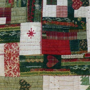 Könnte beinhalten: Eine rechteckige Patchwork-Decke aus verschiedenen Stoffquadraten und -rechtecken in den Farben Rot, Grün, Weiß und Beige. Die Decke enthält verschiedene Muster wie Karos, Blumen und unifarbene Stoffe sowie dekorative Stickereien und Applikationen.