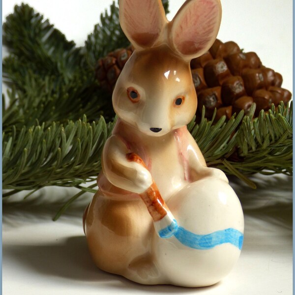 Small Vintage Ceramic Brown Bunny Figurine Wearing Pink Vest Painting a Blue Stripe An Easter Egg