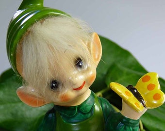 Seated Baby Green Elf Pixie Leprechaun Figurine Holding Shamrocks Clovers Peapod Green Suit Flower Hat Brown Hair Japan 1970s