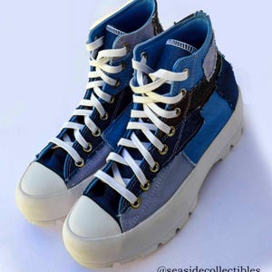 May include: High-top sneakers featuring a patchwork design in various shades of blue canvas, white laces, brass-tone eyelets, and a thick, white lugged rubber sole. The text @seasidecollectibles is visible in the bottom right corner of the image.