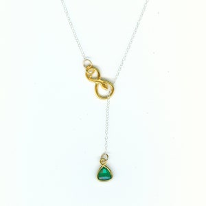 May include: A silver chain necklace with a gold snake infinity charm and a green gemstone pendant.