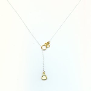 May include: A silver chain necklace with a gold pendant featuring a cluster of interconnected circles and a single teardrop-shaped gemstone.