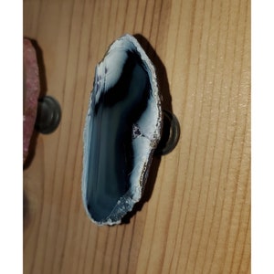 May include: A dark blue and white agate slice mounted on a metal knob. This natural stone knob is a unique and stylish addition to any home decor.