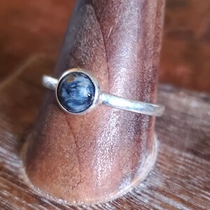 Puede incluir: Un anillo de plata con una piedra preciosa de ojo de tigre azul y marrón.