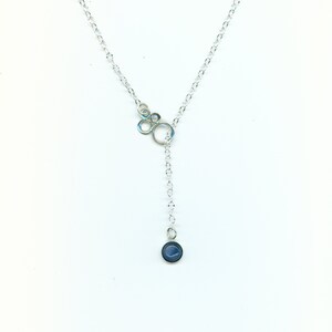 May include: A silver chain necklace with a cluster of small circles at the top and a single blue stone pendant at the bottom.