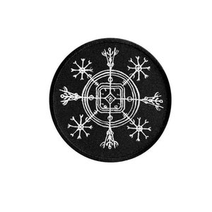 Puede incluir: Un parche redondo negro con un diseño geométrico blanco intrincado. El diseño presenta un cuadrado central, rodeado de círculos y líneas radiales con elementos estilizados en forma de copo de nieve. El parche es probablemente para ropa o accesorios.