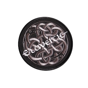 Könnte beinhalten: Ein schwarzer und silberner gestickter Aufnäher mit einem keltischen Knotendesign. Der Aufnäher ist rund und hat einen schwarzen Rand.