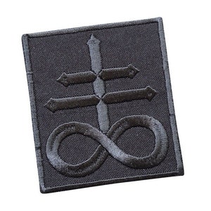 May include: Black embroidered patch featuring a symbol of a cross with an infinity symbol beneath it. The symbol is a dark grey colour and is embroidered on a black fabric background.