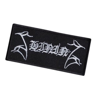 Peut inclure: Écusson brodé noir avec le mot "SLAYER" en lettres blanches. Les lettres sont dans une police stylisée avec un design gothique.