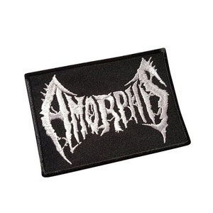May include: Black embroidered patch with the word "AMORPHIS" in white lettering. The lettering is in a stylized, gothic font.
