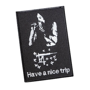 Könnte beinhalten: Schwarzer gestickter Aufnäher mit einer weißen Silhouette einer Person, die eine Spritze hält, und dem Text "Have a nice trip".