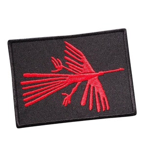 Puede incluir: Parche bordado rojo con un diseño de pájaro estilizado sobre un fondo negro.