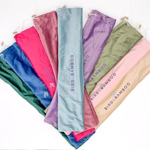 May include: A collection of long, rectangular fabric storage bags arranged in a fan shape. The bags come in various colors including green, blue, pink, mauve, light blue, purple, olive, and beige, each featuring the text BIRD & BAMBOO.