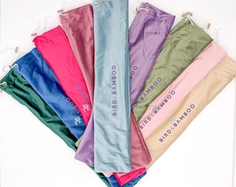 May include: A collection of long, rectangular fabric storage bags arranged in a fan shape. The bags come in various colors including green, blue, pink, mauve, light blue, purple, olive, and beige, each featuring the text BIRD & BAMBOO.