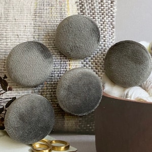 May include: Five grey velvet buttons with a textured surface.