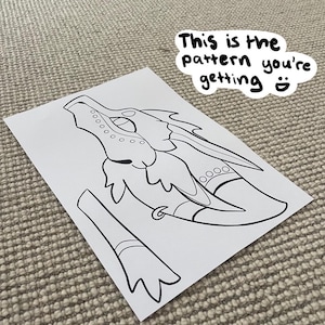 May include: A printable dragon head craft pattern. The pattern is black and white and includes a head, wings, and a tail.