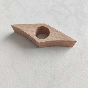 Peut inclure: Un marque-page en bois en forme de diamant avec un trou rond au centre. Le marque-page est en bois brun clair.