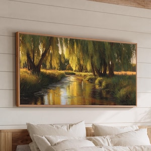 May include: A framed landscape painting depicts a serene river scene with weeping willow trees. The artwork features warm tones of gold, green, and brown, creating a tranquil and natural ambiance. The painting is displayed above a bed with neutral-colored bedding.