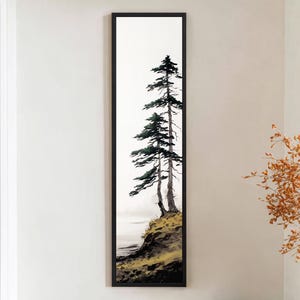 May include: A vertical framed art print featuring two tall evergreen trees on a hillside. The artwork has a minimalist style with a white background and a black frame. The trees are green and the hillside is a mix of yellow and brown.