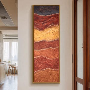 May include: Abstract rectangular artwork with a gold frame. The painting features horizontal bands of color, including dark blue, red, yellow, and orange. The textured surface creates a layered effect, resembling a landscape.