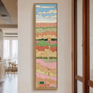May include: Vertical abstract mosaic art piece in a gold frame. The artwork features a landscape design with blue sky and clouds at the top, followed by layers of earth tones, greens, and pinks. The mosaic is composed of irregular, colorful tiles.