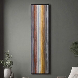 May include: Vertical abstract art piece in a black frame. The artwork features a series of vertical stripes in shades of red, blue, yellow, and gray. The piece is displayed on a gray wall, adding a touch of color to the room.