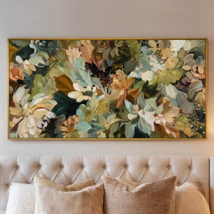 May include: An abstract floral painting in a gold frame. The artwork features a mix of white, green, and peach-colored flowers and foliage. The painting is rectangular and hangs above a bed with beige pillows.