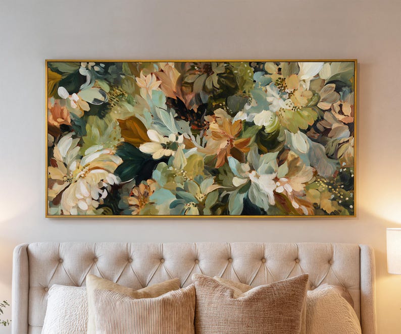 May include: An abstract floral painting in a gold frame. The artwork features a mix of white, green, and peach-colored flowers and foliage. The painting is rectangular and hangs above a bed with beige pillows.