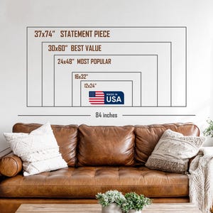 May include: A brown leather sofa with decorative pillows and a blanket. Above the sofa, a white wall displays a series of rectangular outlines with text indicating sizes such as "37x74" STATEMENT PIECE" and "MADE IN USA". The total width is 84 inches.