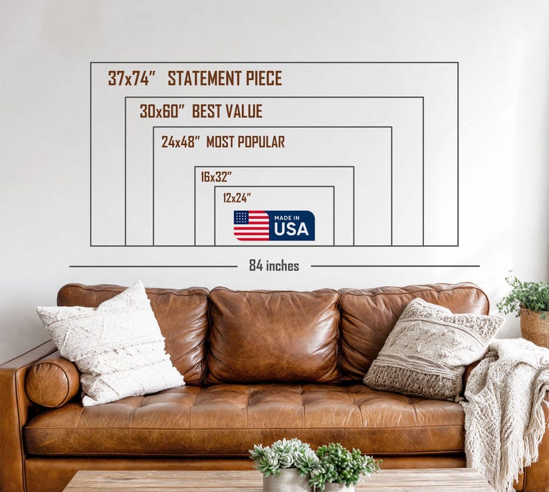 May include: A brown leather sofa with decorative pillows and a blanket. Above the sofa, a white wall displays a series of rectangular outlines with text indicating sizes such as "37x74" STATEMENT PIECE" and "MADE IN USA". The total width is 84 inches.