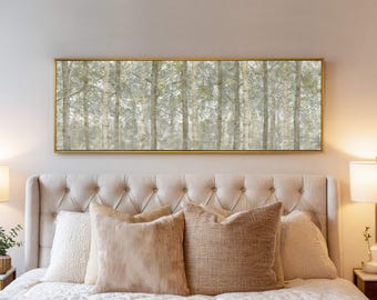 May include: A rectangular framed artwork featuring a forest scene with tall, slender trees. The trees have light-colored bark and are set against a soft, muted background. The artwork is displayed above a bed with beige pillows.
