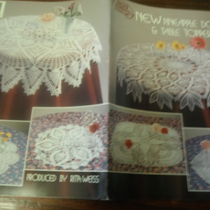 May include: A craft pattern book titled New Pineapple Doilies & Table Toppers produced by Rita Weiss. The cover features multiple photographs of white crocheted doilies and table toppers with intricate pineapple motifs displayed on tables.