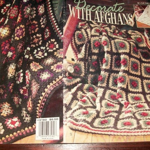 May include: A craft book titled Decorate With Afghans featuring 10 designs. The cover displays two crocheted blankets made of granny squares in dark brown, red, and cream colors. A barcode with the number 3160 is visible on the lower left corner.