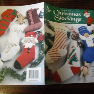May include: A crochet pattern book titled Crochet Christmas Stockings featuring eight designs. The cover displays various handmade stockings in red, white, blue, and brown, decorated with motifs like Santa, an angel, and a Christmas tree.