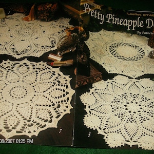 May include: A leaflet titled "Pretty Pineapple Doilies" featuring seven crochet doily designs. The doilies are cream-colored, with intricate pineapple patterns. The leaflet includes the date 01/08/2007 and the time 01:25 PM.